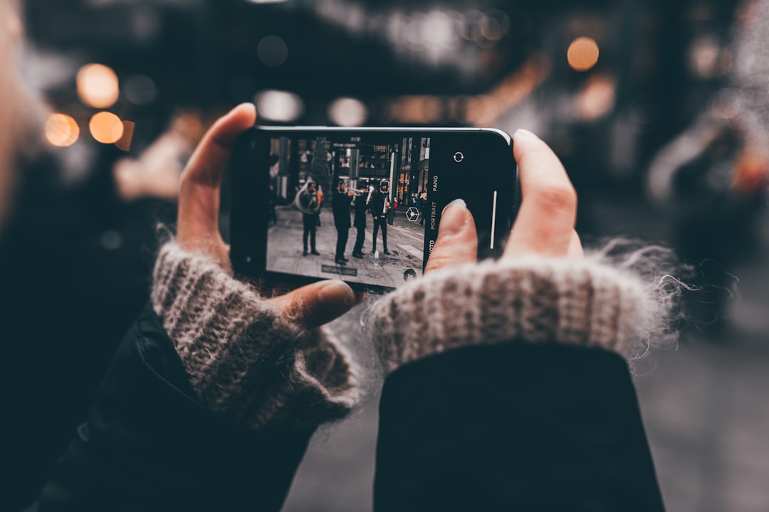 person using smartphone camera on people during day