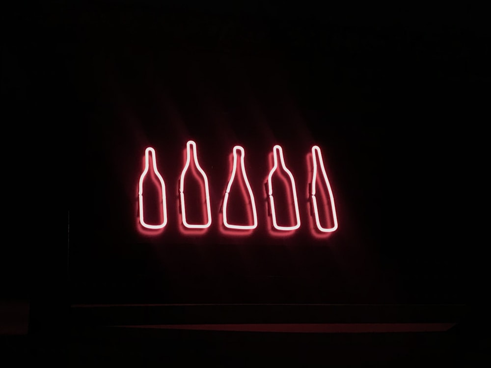 a neon sign with six bottles in it
