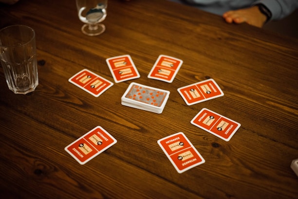 Close-up of hands placing rummy cards on a table with a laptop displaying Waving Rummy website.