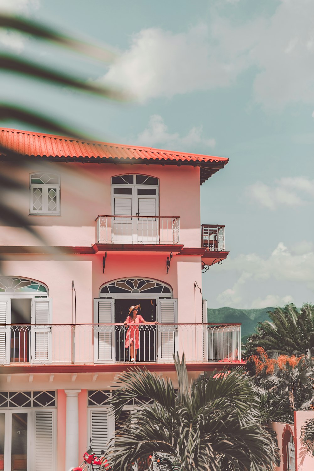 a pink house with a red roof and balcony