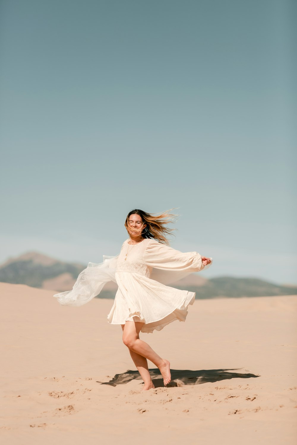 Mujer en vestido blanco de pie en el desierto