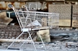 gray metal shopping cart by concrete wall at daytime