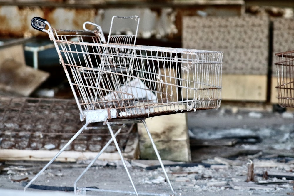 chariot d’achat en métal gris par mur en béton pendant la journée