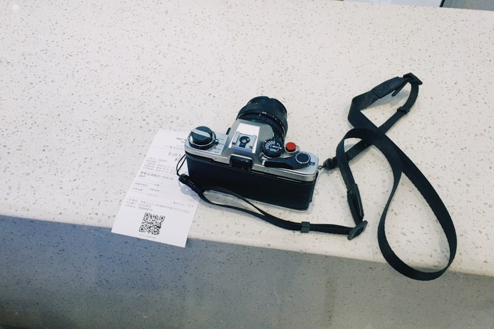 black and gray DSLR camera with strap on top of receipt
