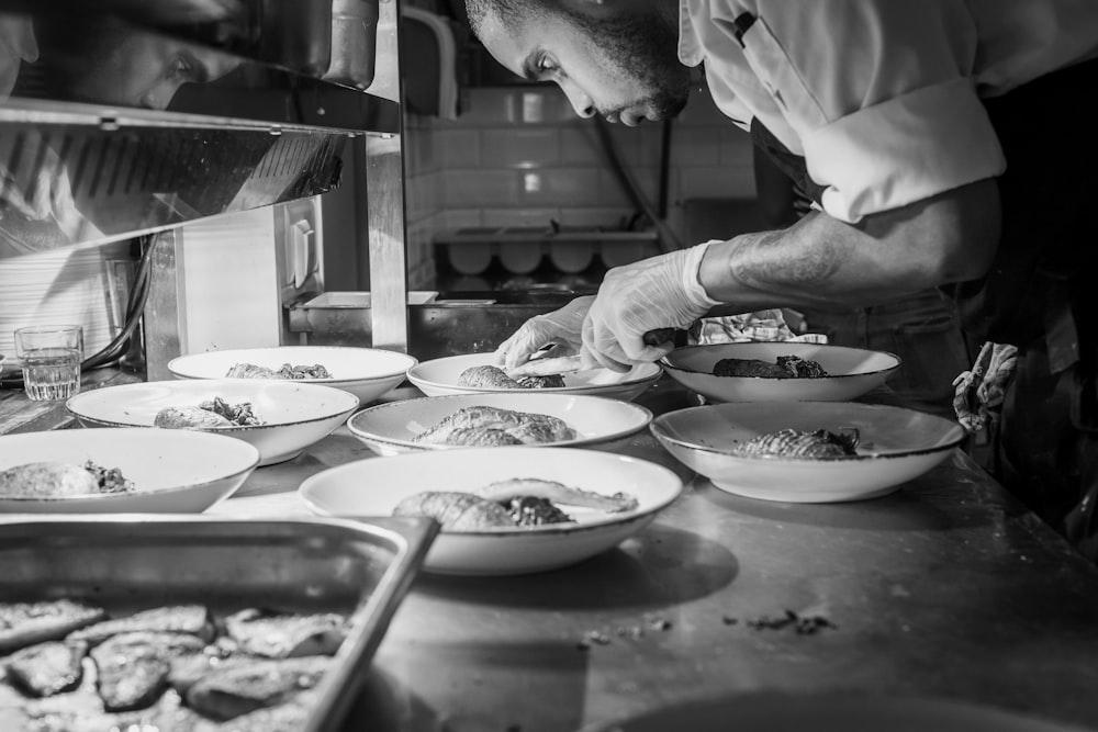 grayscale photography of person doing plating of dishes