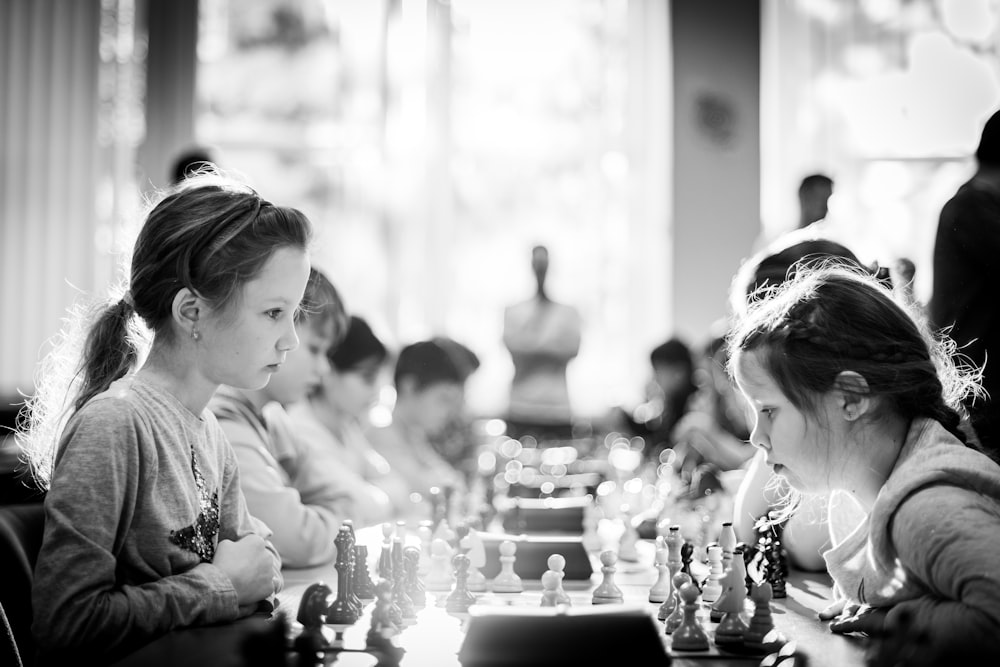 grayscale photography of children sitting while playing chess