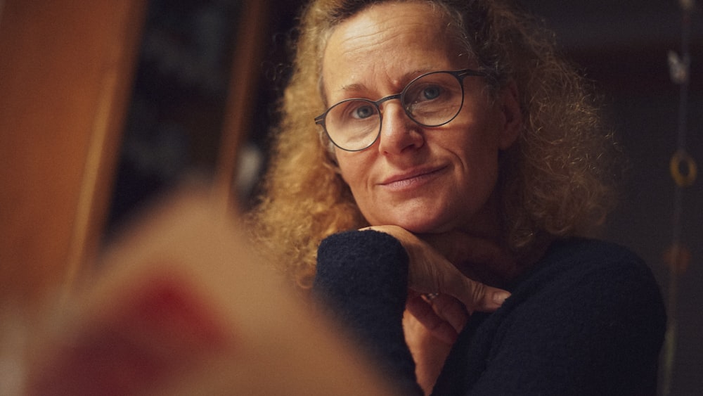 a woman wearing glasses looking at a mirror