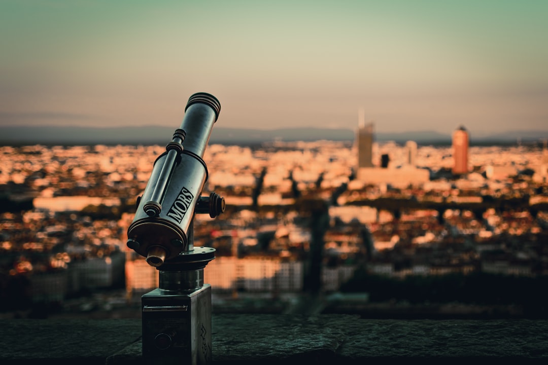 selective focus photography of telescope by cityscape during daytime