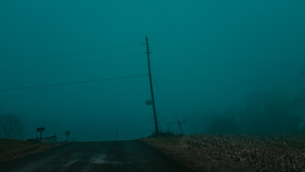 an empty road in the middle of a foggy field