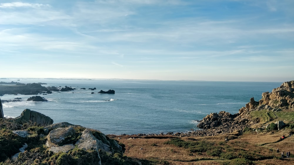 landscape photography of cliff viewing blue sea under blue and white sky