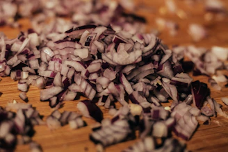 Fresh onion flakes spilling gently from a transparent pouch onto a wooden surface.