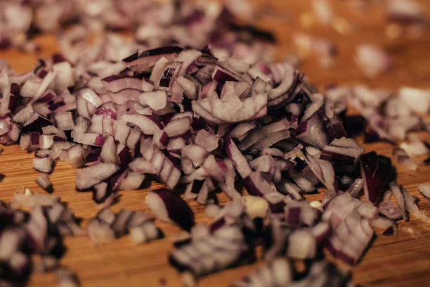 Fresh onion flakes spilling gently from a transparent pouch onto a wooden surface.