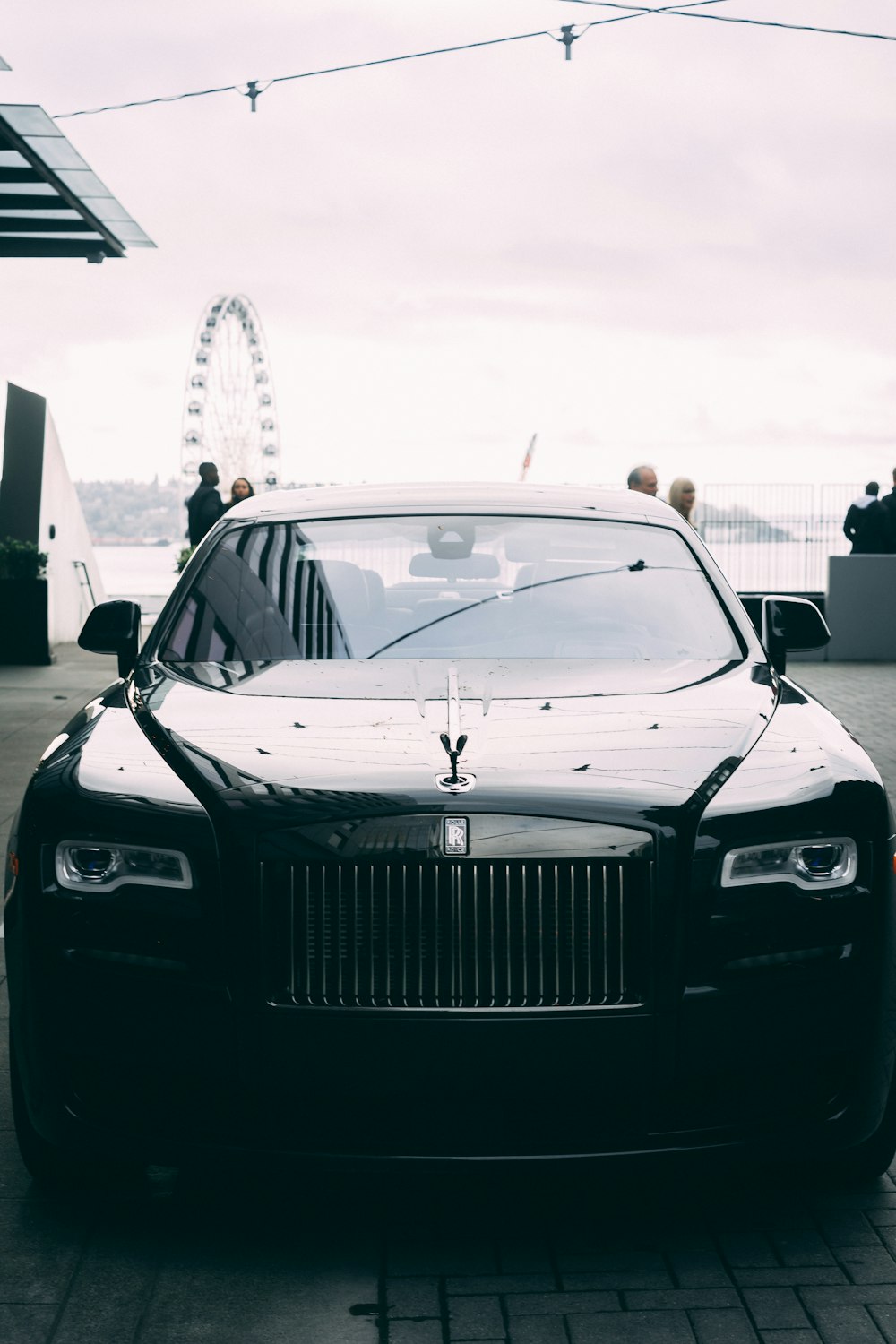 black Bentley luxury car parked on road near sidewalk