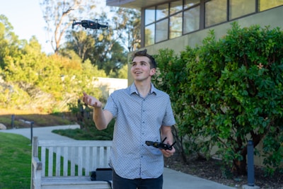A young mentee smiling proudly as they pilot a small drone under the guidance of a veteran mentor.