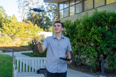 A smiling technician operating a drone with lush green Caribbean foliage in the background.