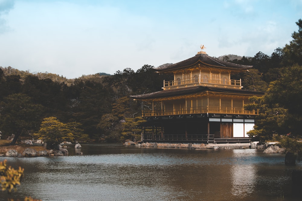 Kinkaku-ji in Japan surrounded with green trees under blue and white sky