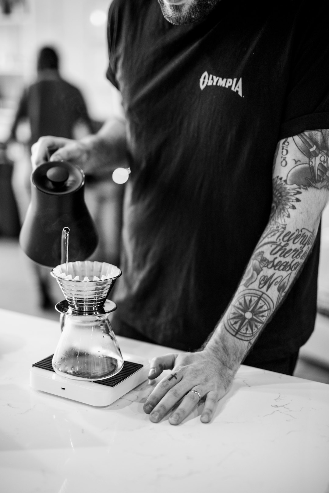 person holding pitcher pouring liquid into bottle