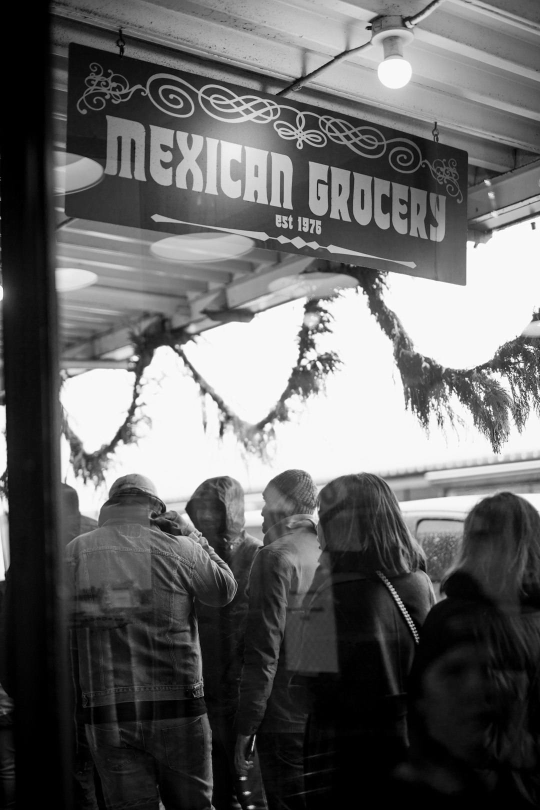 grayscale photography of people standing outside Mexican Grocery building