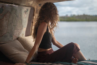 woman wearing black spaghetti strap top sitting viewing body of water