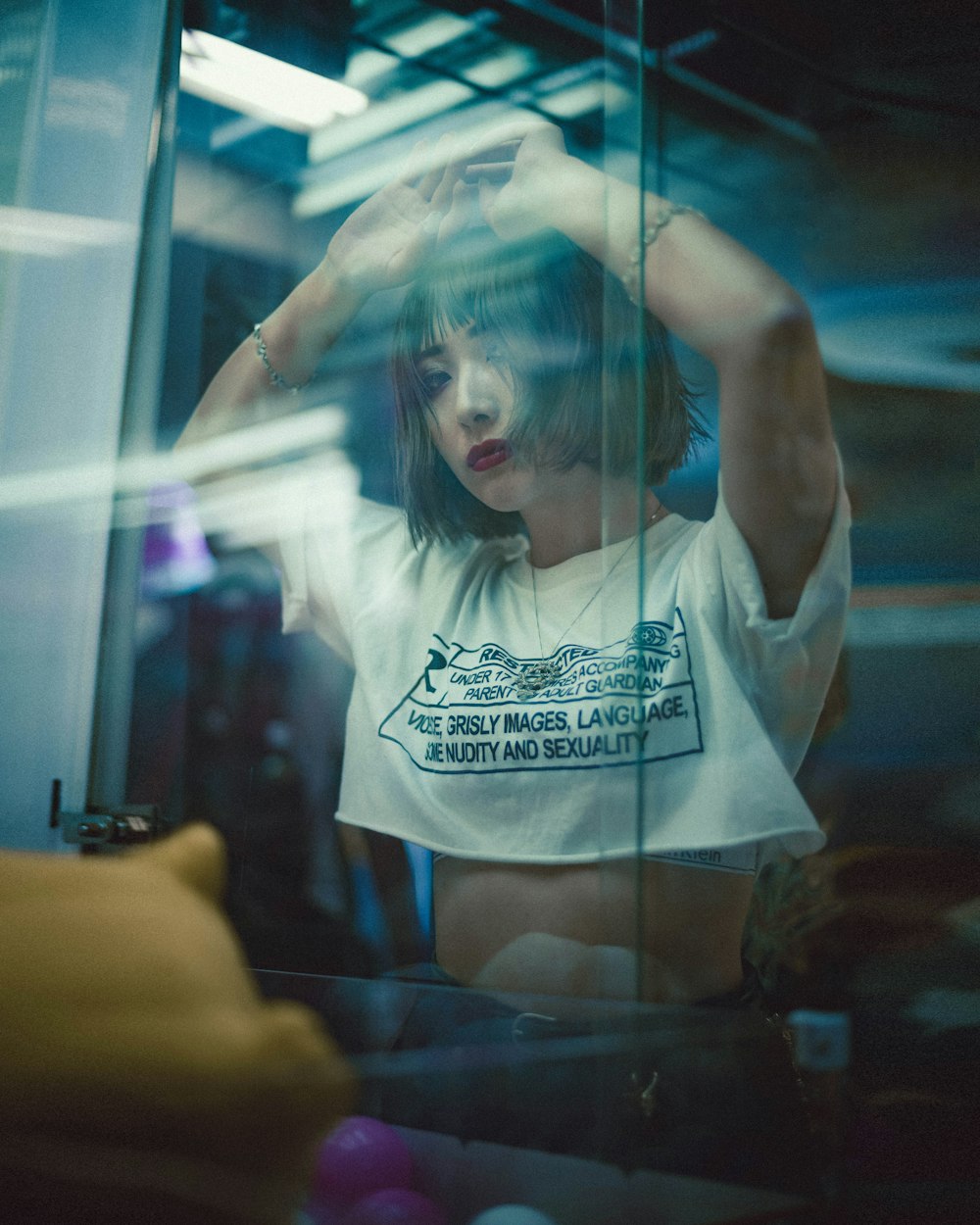 woman wearing white and black printed crew-neck crop top standing and leaning on glass wall