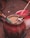 A large, red container filled with some kind of grain or powder with several sticks inserted into it. The container looks old and worn. In the background, there is another white and red container on a dirt surface.