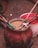 A large, red container filled with some kind of grain or powder with several sticks inserted into it. The container looks old and worn. In the background, there is another white and red container on a dirt surface.