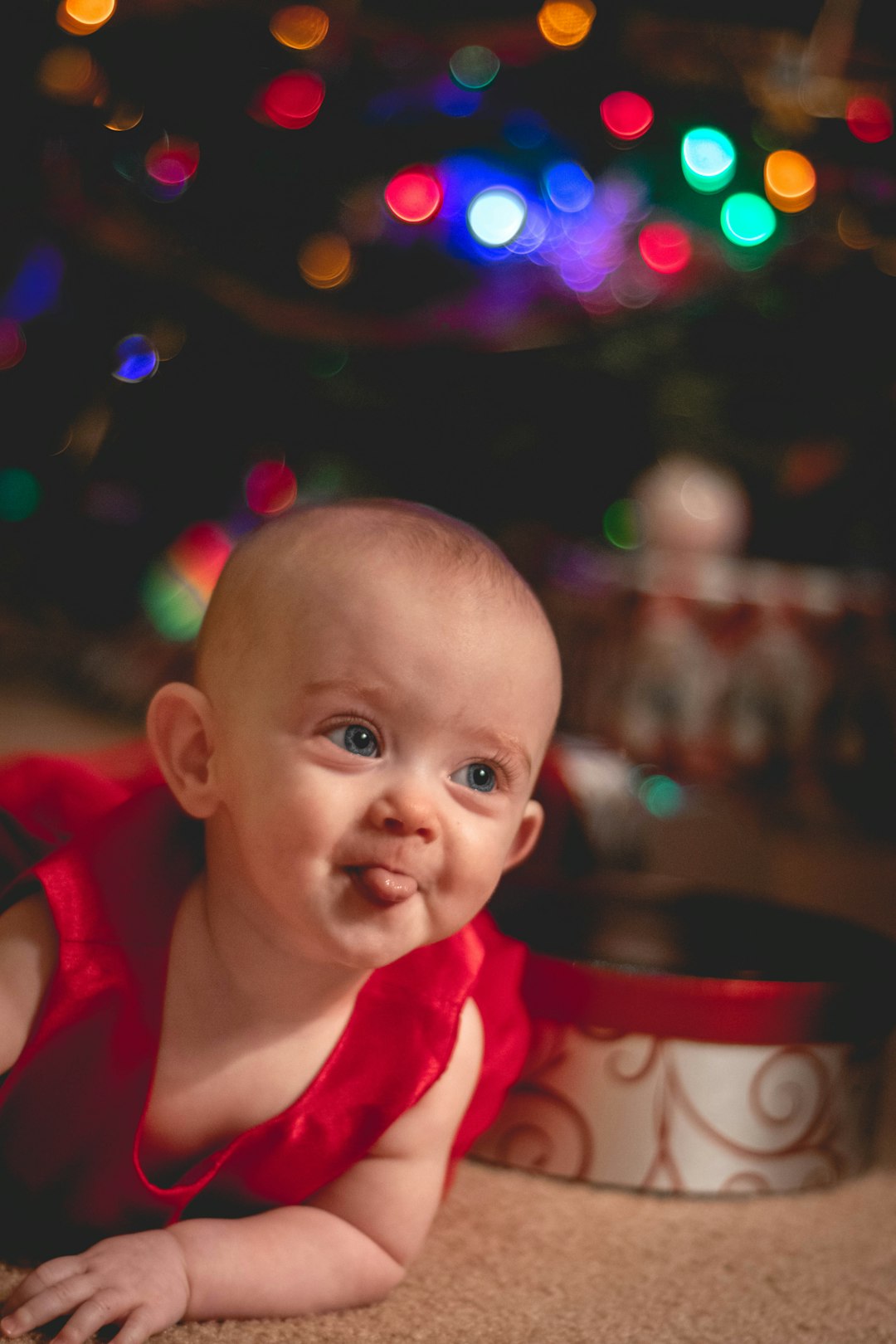 child sticking tongue out by Christmas tree