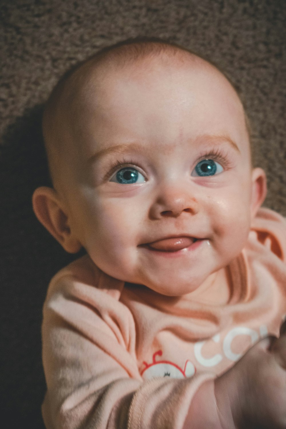 Bebé con chaqueta estampada beige y blanca sonriendo