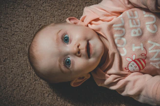 smiling child in long-sleeved top lying on brown canvas