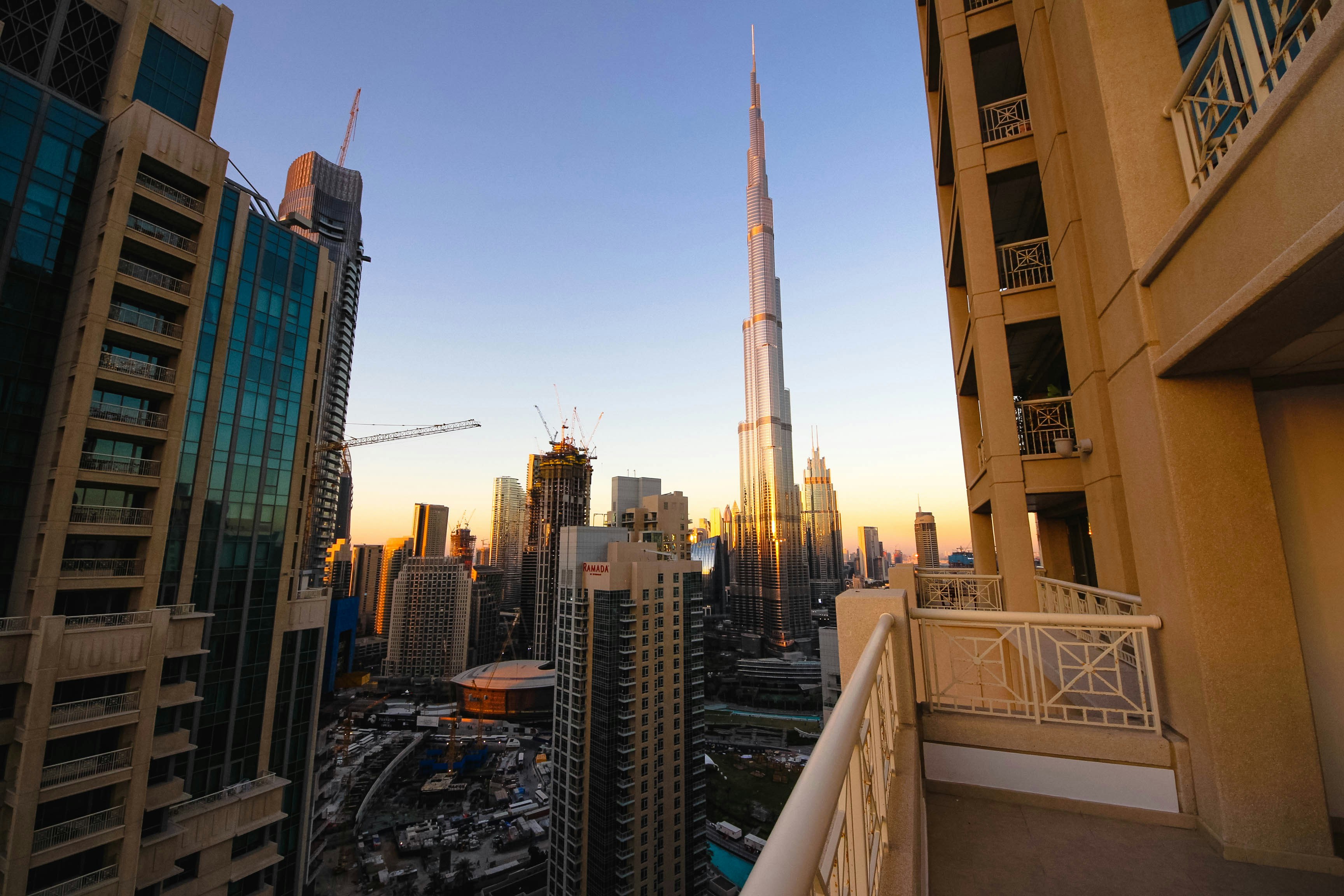 Burj Khalifa se dviga nad obzorjem Dubaja ob sončnem zahodu z zlatimi odtenki