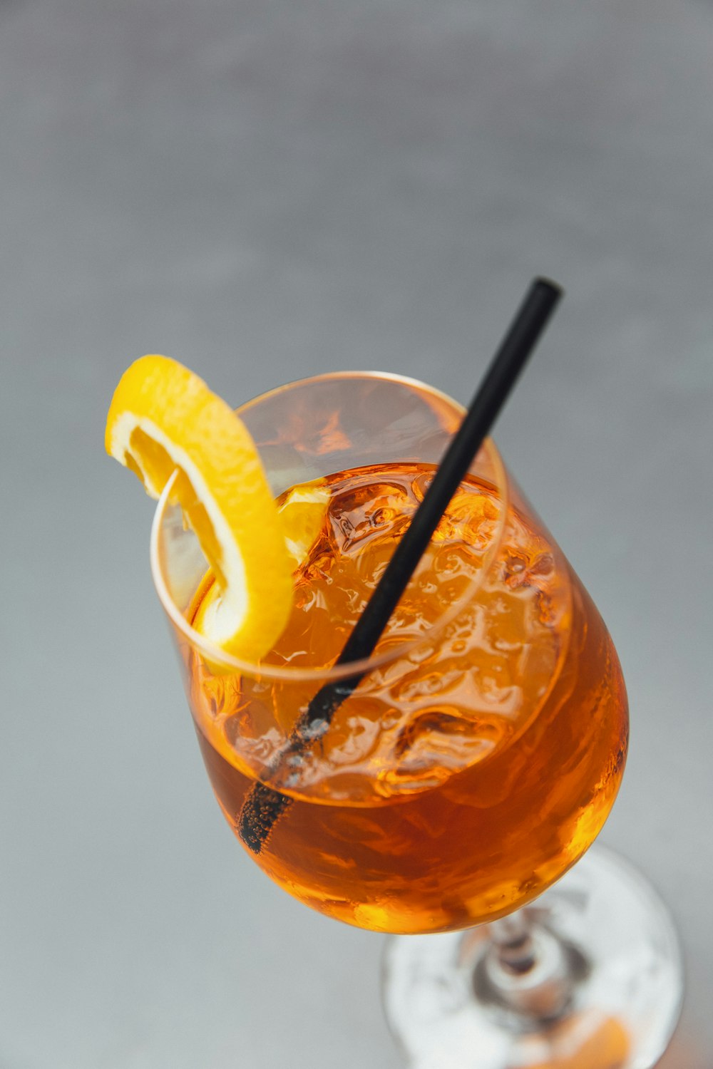 3/4 filled long-stem glass cup with straw and slice of orange