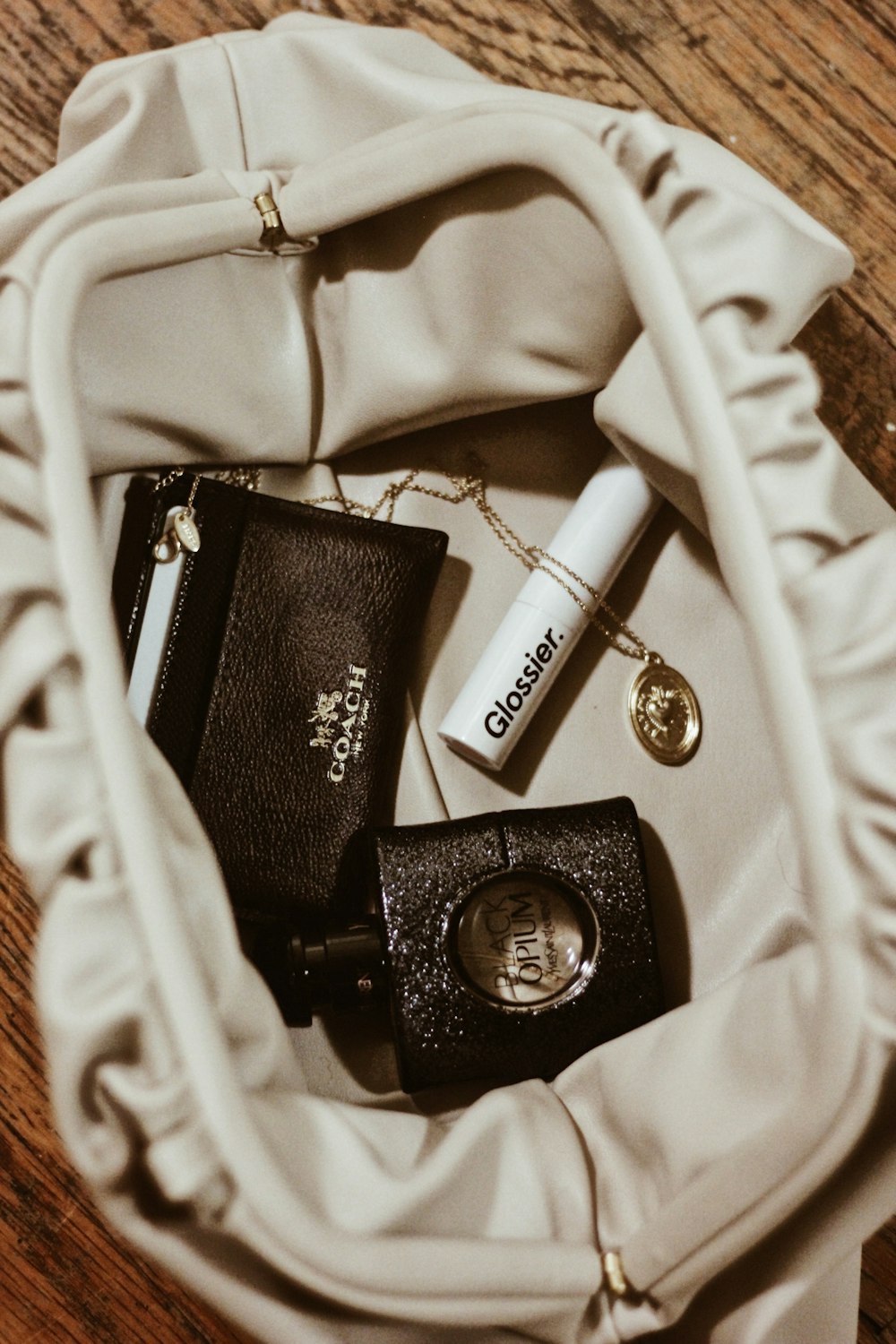 gold-colored necklace near lip gloss, wallet, and spray bottle