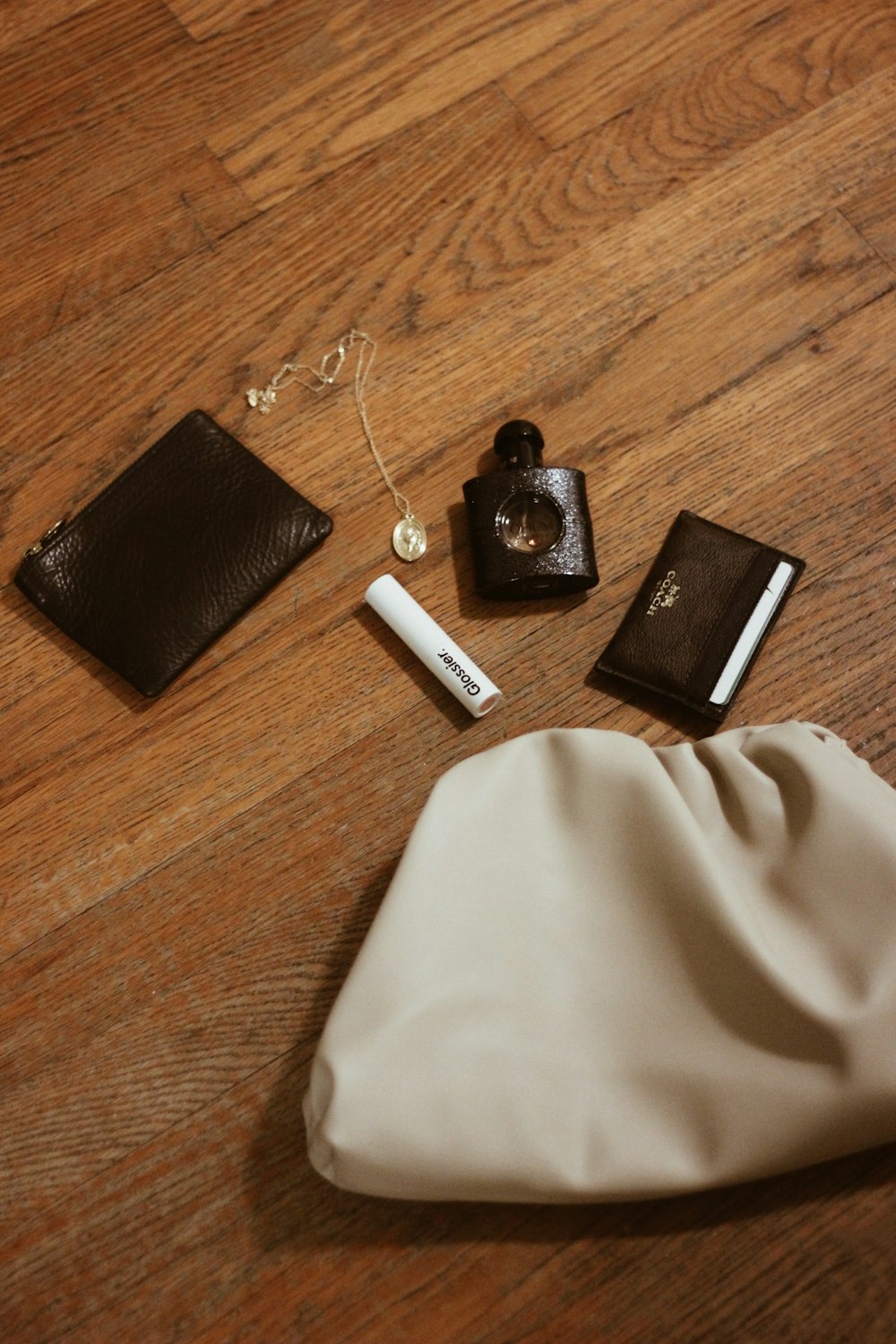 black wallet near spray bottle, necklace, and coin purse