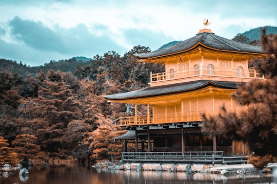 view of pagoda by water and trees in Kinkaku-ji Japan