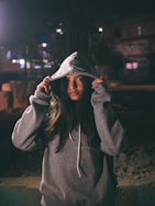 woman in hoodie while both hands holding the hood