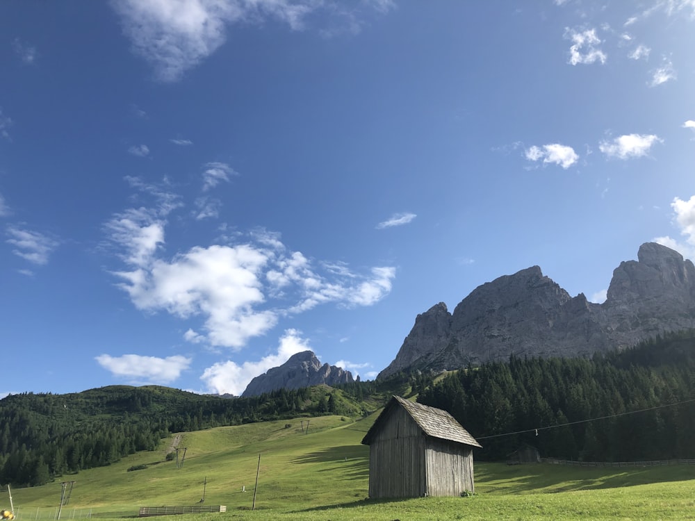 shack on green field near forest and mountains at daytime