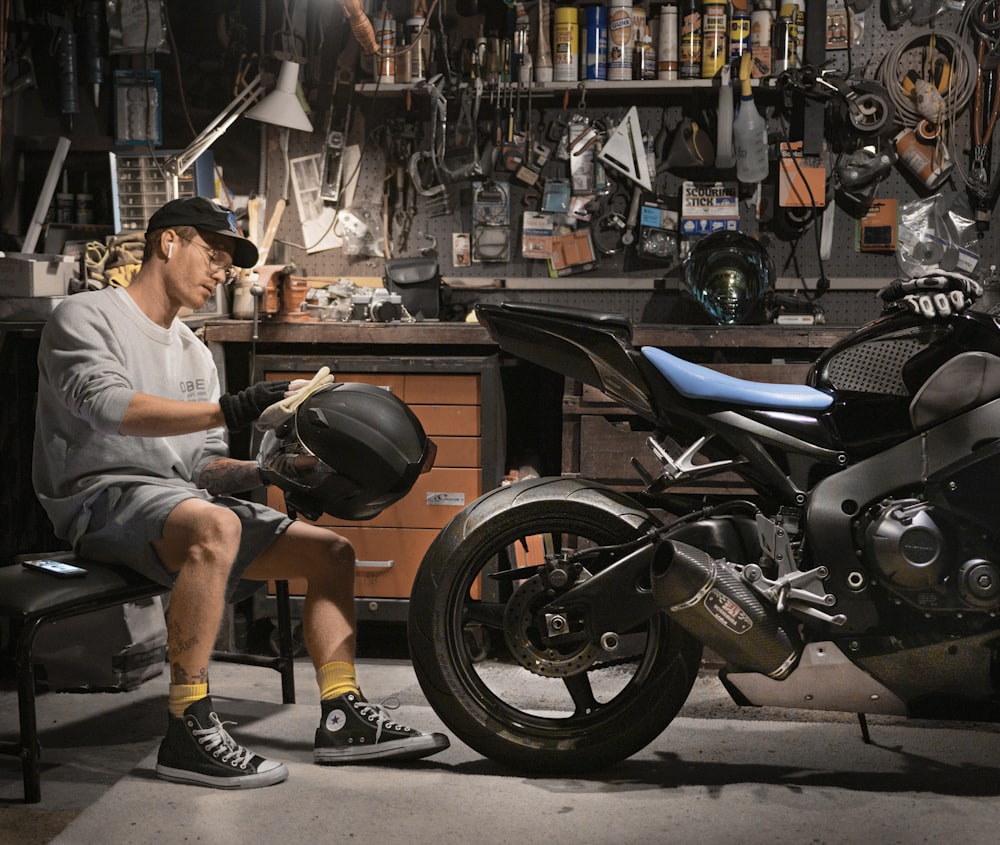 man wiping motorcycle helmet by motorcycle