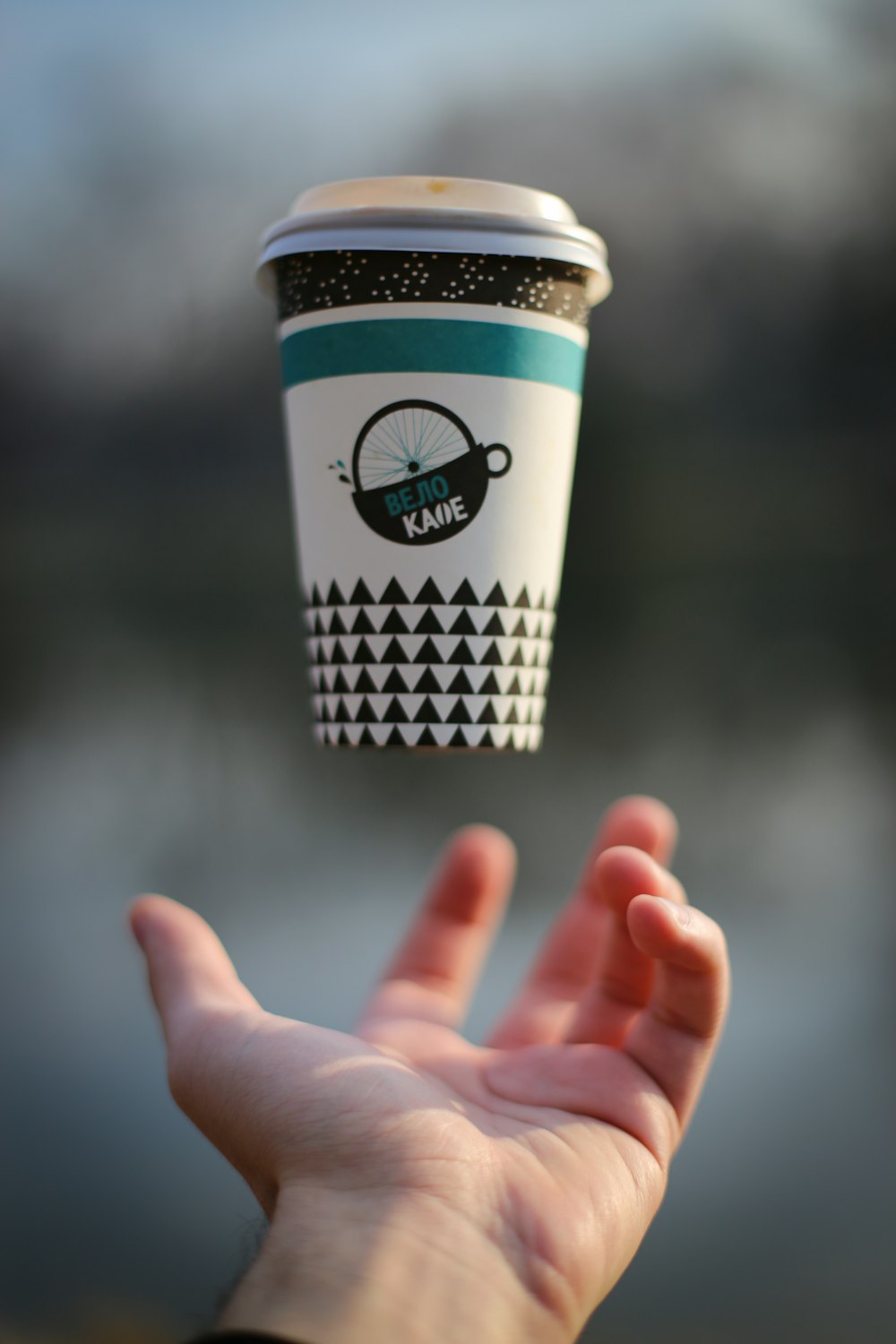 selective focus photography of person tossing paper cup with lid