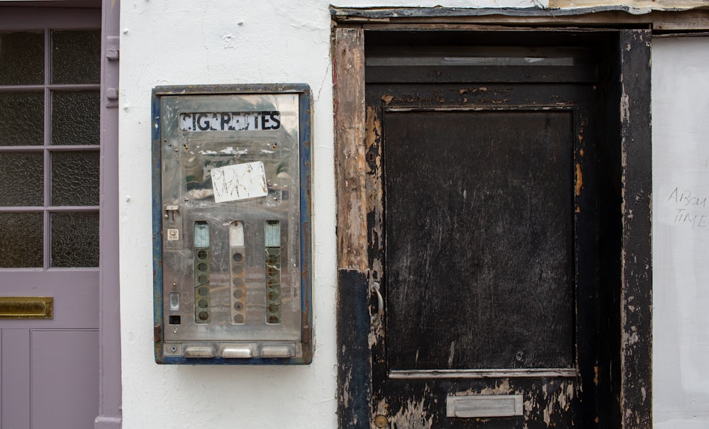 gray metal box beside black wooden door