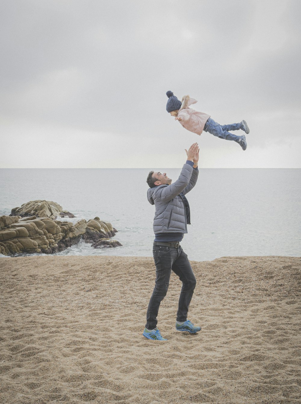 man playing with toddler on shore