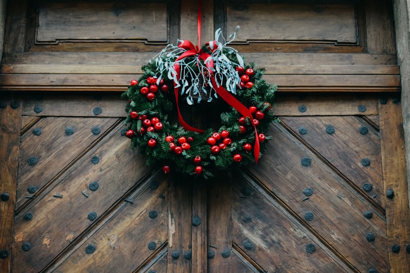 green and red wreath on brown wooden door