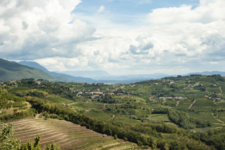 A panoramic view of rolling hills in the Apennines with rustic houses scattered among lush greenery.