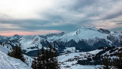 A panoramic view of snow-capped Atlas Mountains with a traditional Berber village nestled below.
