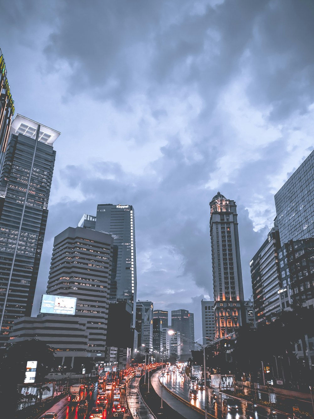 a city street filled with lots of traffic under a cloudy sky