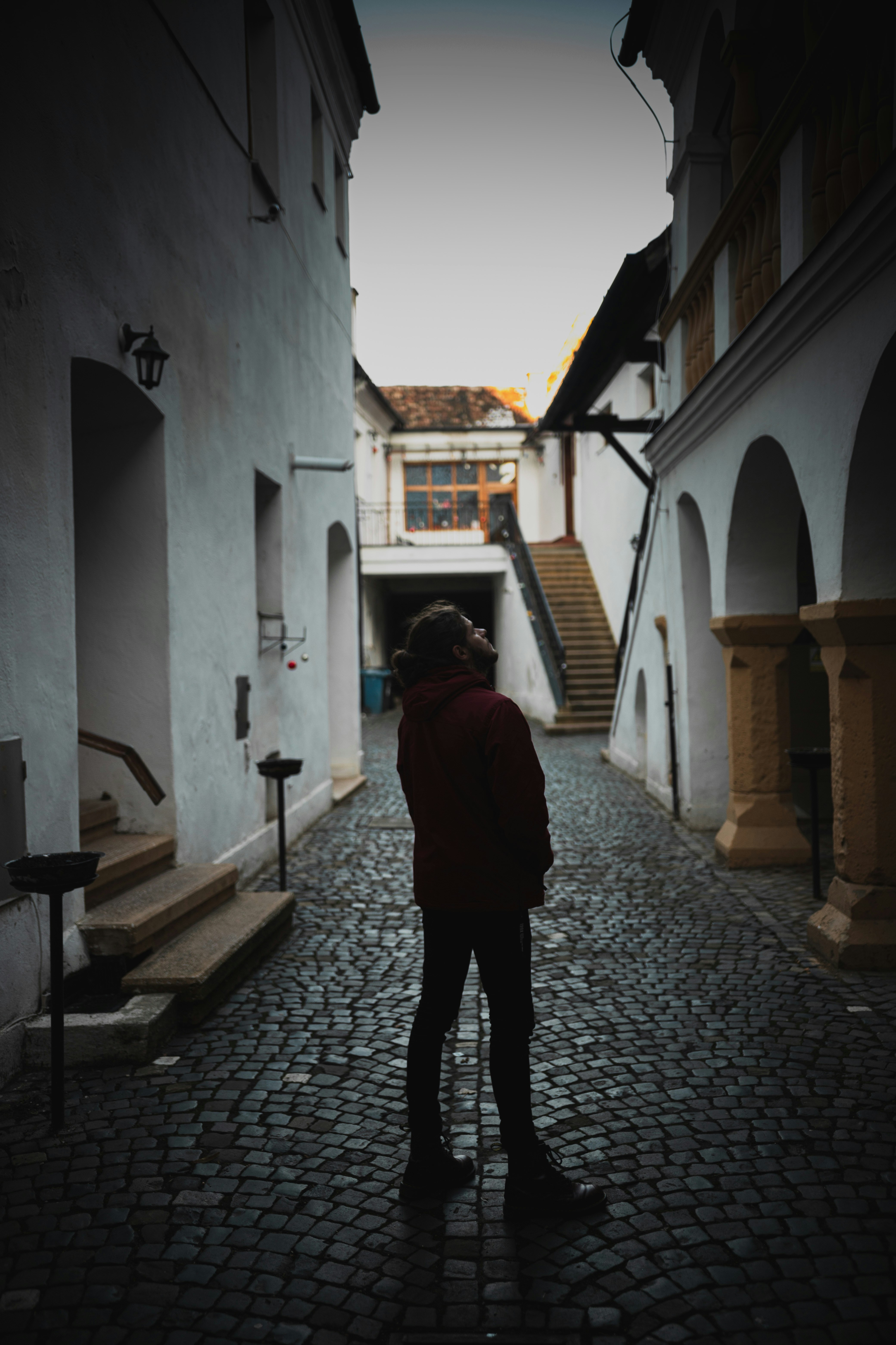uma pessoa em pé em uma rua de paralelepípedos