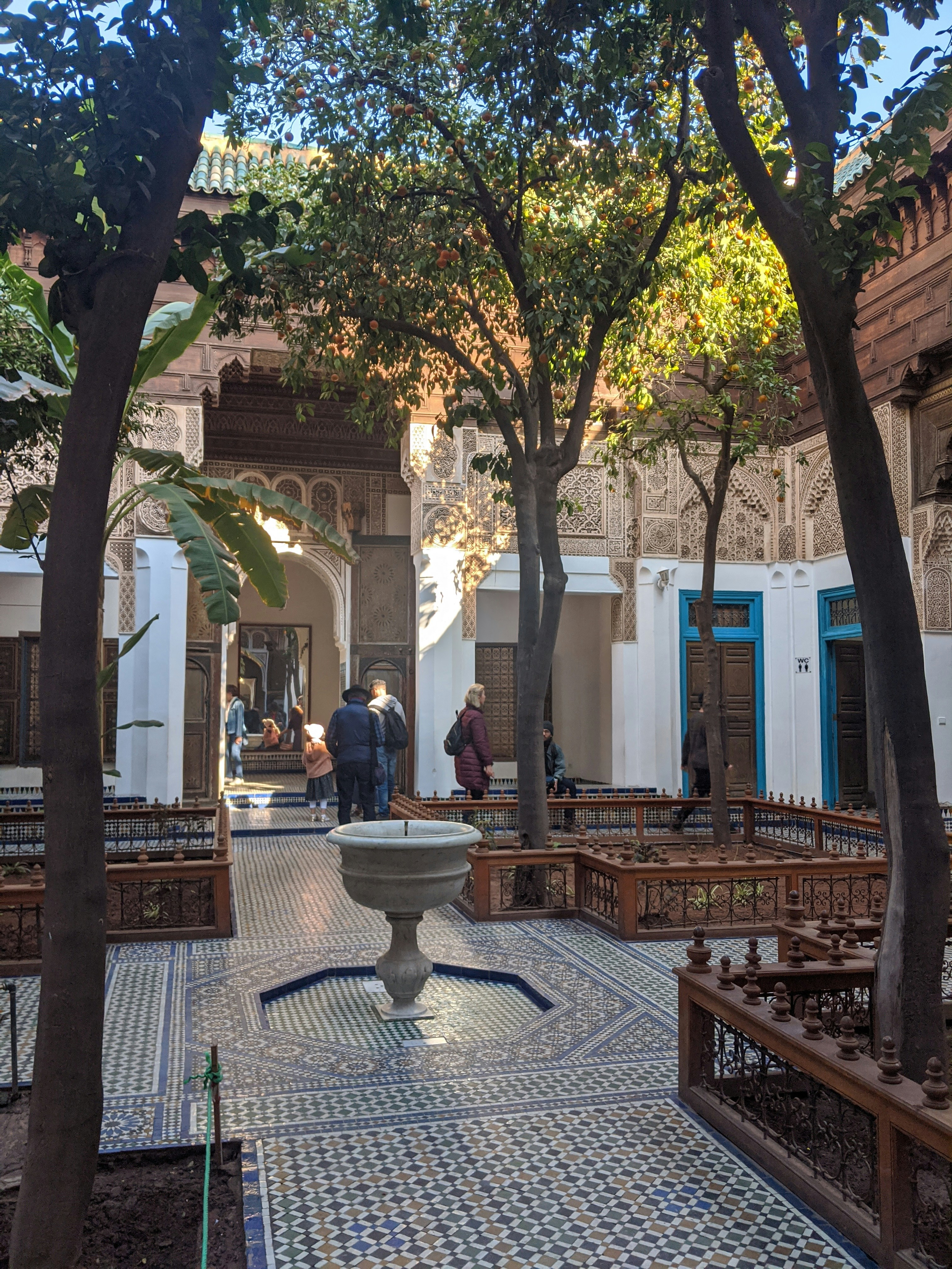 Elegant boutique hotel courtyard with Andalusian tiles, central fountain, lush orange trees, soft evening lighting, warm terracotta walls