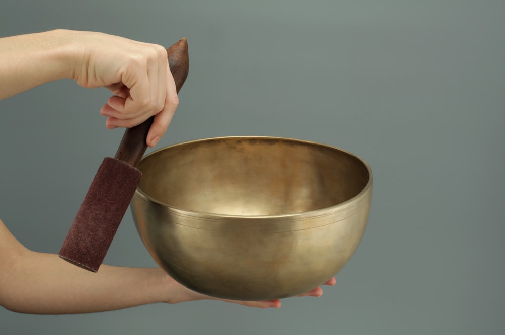 person holding brass-colored song bowl set