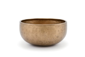 A polished brass singing bowl with a smooth, rounded shape and a slightly matte finish. It has a simple design with no intricate patterns, placed against a plain white background.