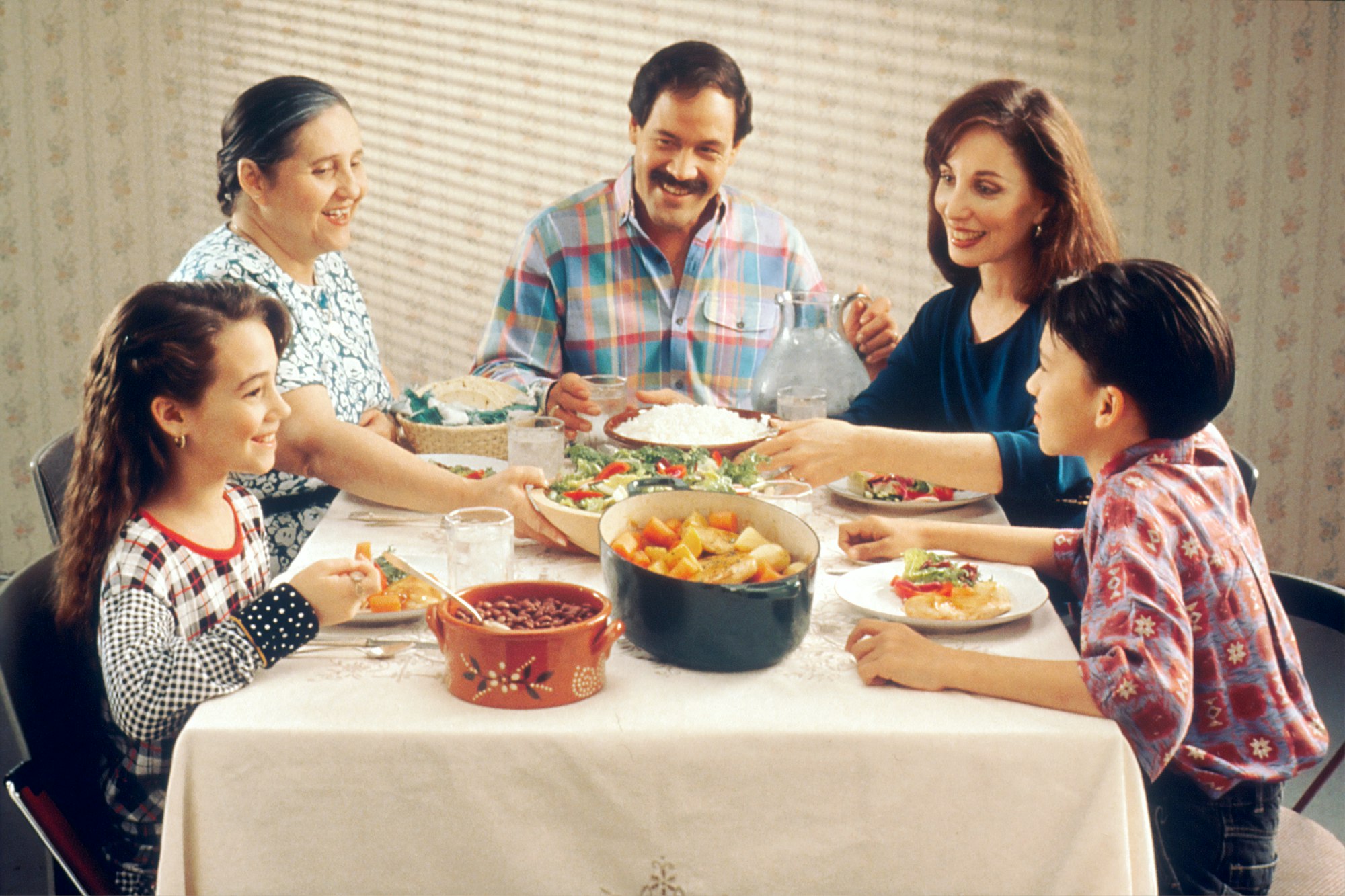 Family Eating Meal. A Hispanic family (male adult, two female adults, female child, and male child) enjoy a meal at the dinner table.