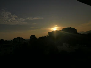 A scenic photo of a sunrise behind a city skyline symbolizing new beginnings in cloud technology.